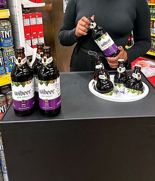 Promotora da Essencial RH segurando uma garrafa em ação de degustação