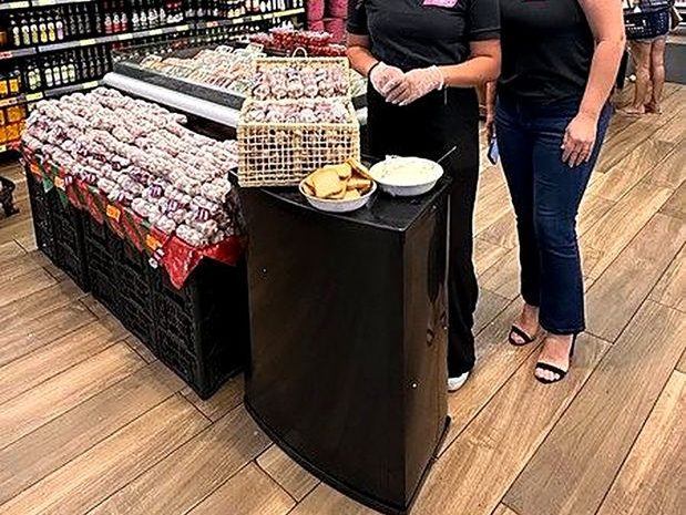 Promotoras uniformizadas da Essencial RH em ponto de degustação no hortifrúti